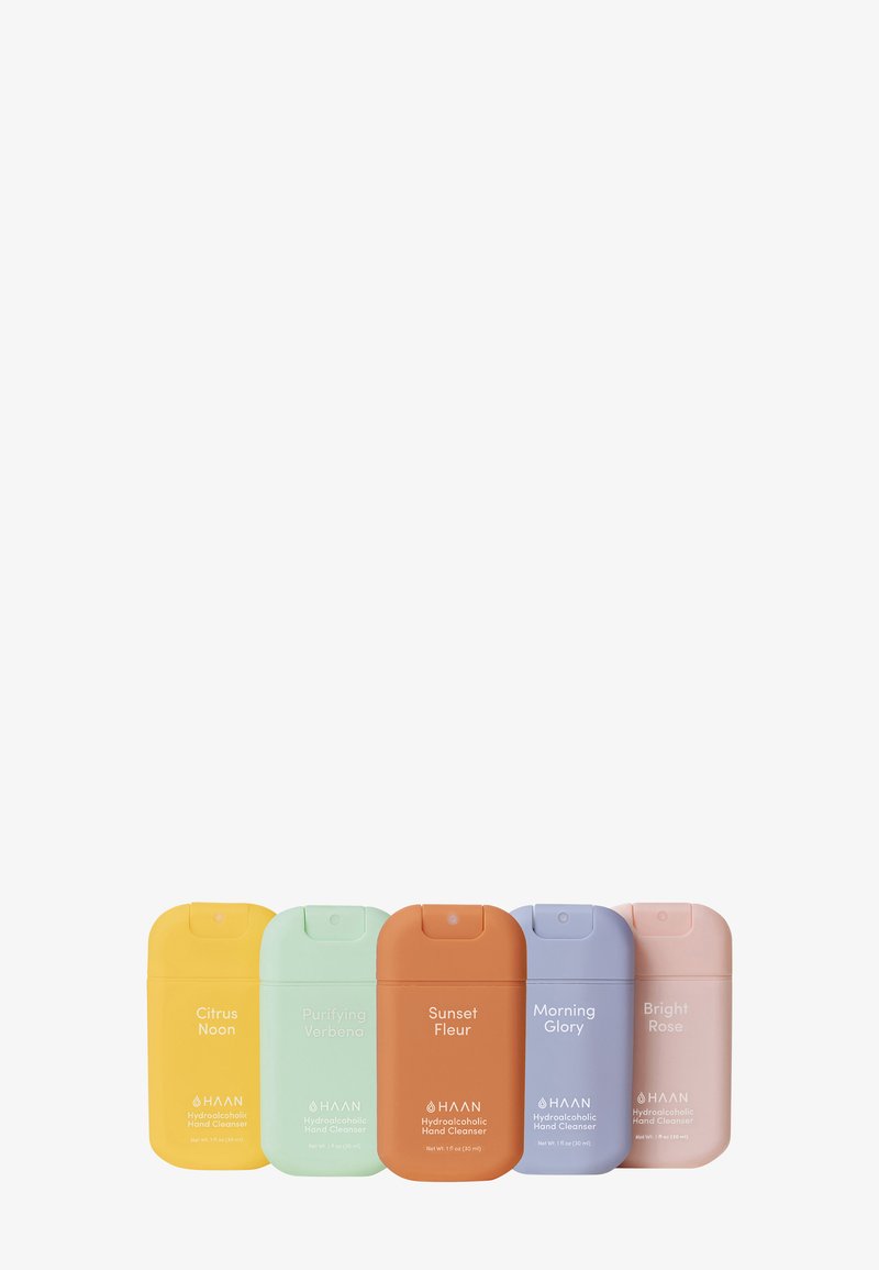Set van vijf flessen handreiniger in pastelkleuren: geel, groen, oranje, paars en roze. Ronde vormen, eenvoudige labels met witte tekst.