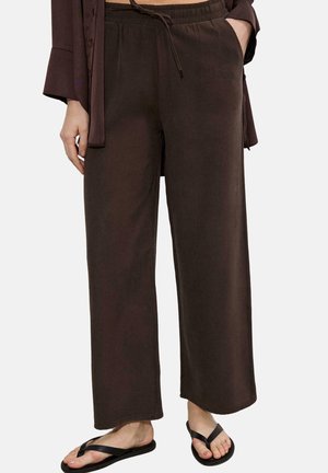 Lahtised tumedat pruunid laiad säärtega püksid, millel on elastne vöökoht ja paelad, kantud mustade plätude ja sobiva tumeda pruuni ülaosaga.