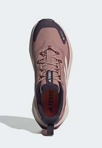 Scarpe da trekking rosa chiaro con tomaia testurizzata, tallone rinforzato e accenti viola scuro. Caratterizzano lacci e un interno imbottito.