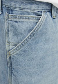 Jeans de mezclilla azul claro con un bolsillo frontal, costuras visibles y una superficie ligeramente texturizada. La tela parece suave y desgastada.