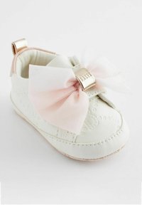 Witte leren babyschoen met een roze strik en gouden hardware. Geweven details aan de zijkanten. Zachte voering en gevoerd kraagje voor comfort.