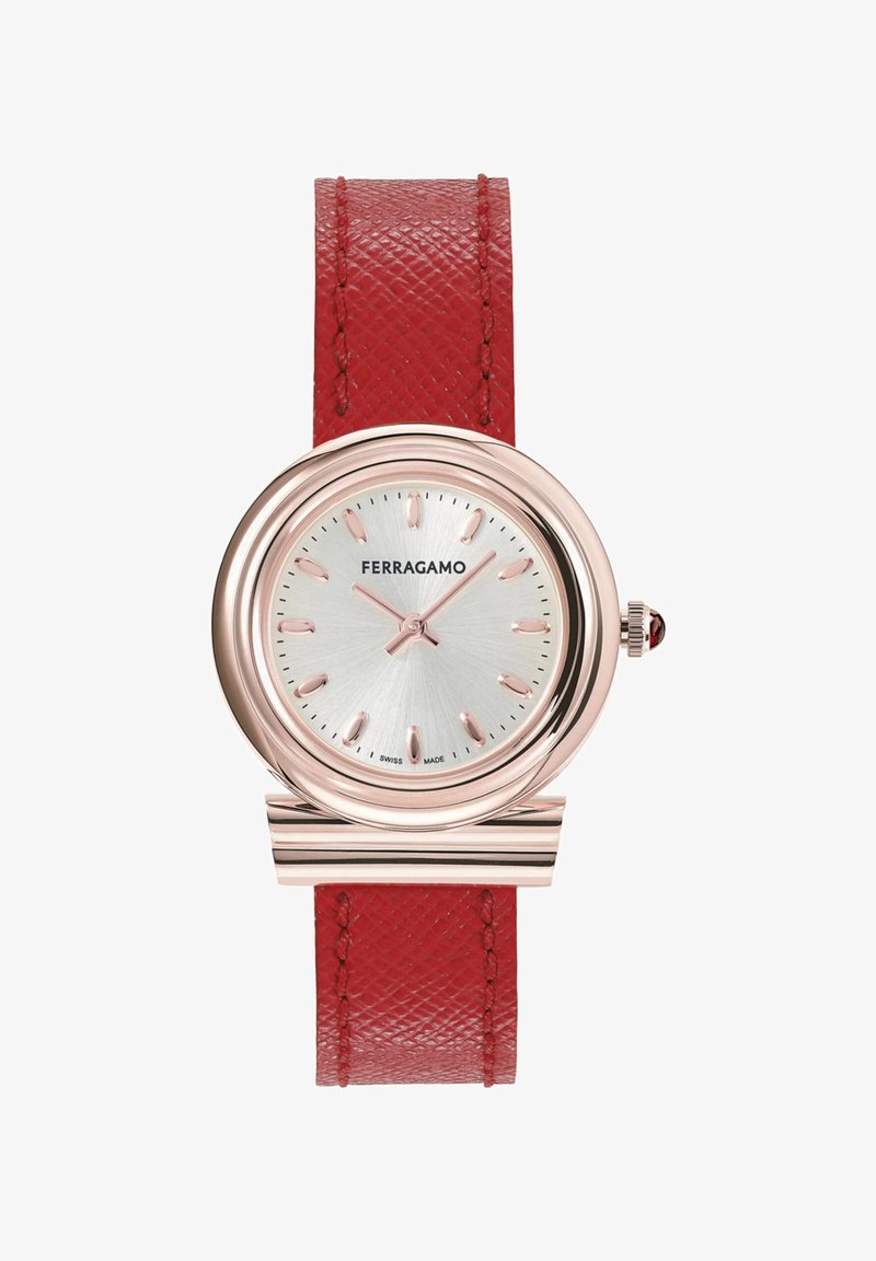 Punane nahast rihmaga kell ümmarguse roosakuldse korpuse, hõbedase tekstuuriga kellasliku ja indekseerimisega tunni markeritega. Omab kabokoni kroonidetaili.