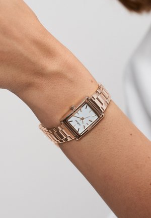 Rechteckige Uhr in Roségold mit weißem Zifferblatt, Metallgliederarmband und schlichten Stundenmarkierungen. Die Uhr verfügt über eine kleine Krone an der Seite.
