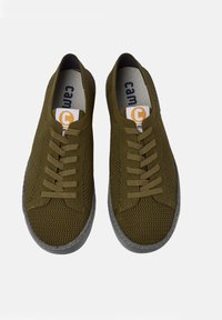 Une paire de baskets basses tricotées vert olive avec fermeture à lacets et semelles en caoutchouc grises sur fond blanc.