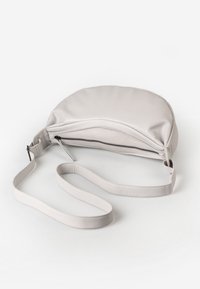 Borsa a tracolla in pelle grigia chiara, forma a mezzaluna, texture liscia, chiusura con zip superiore, tracolla regolabile, design minimalista.