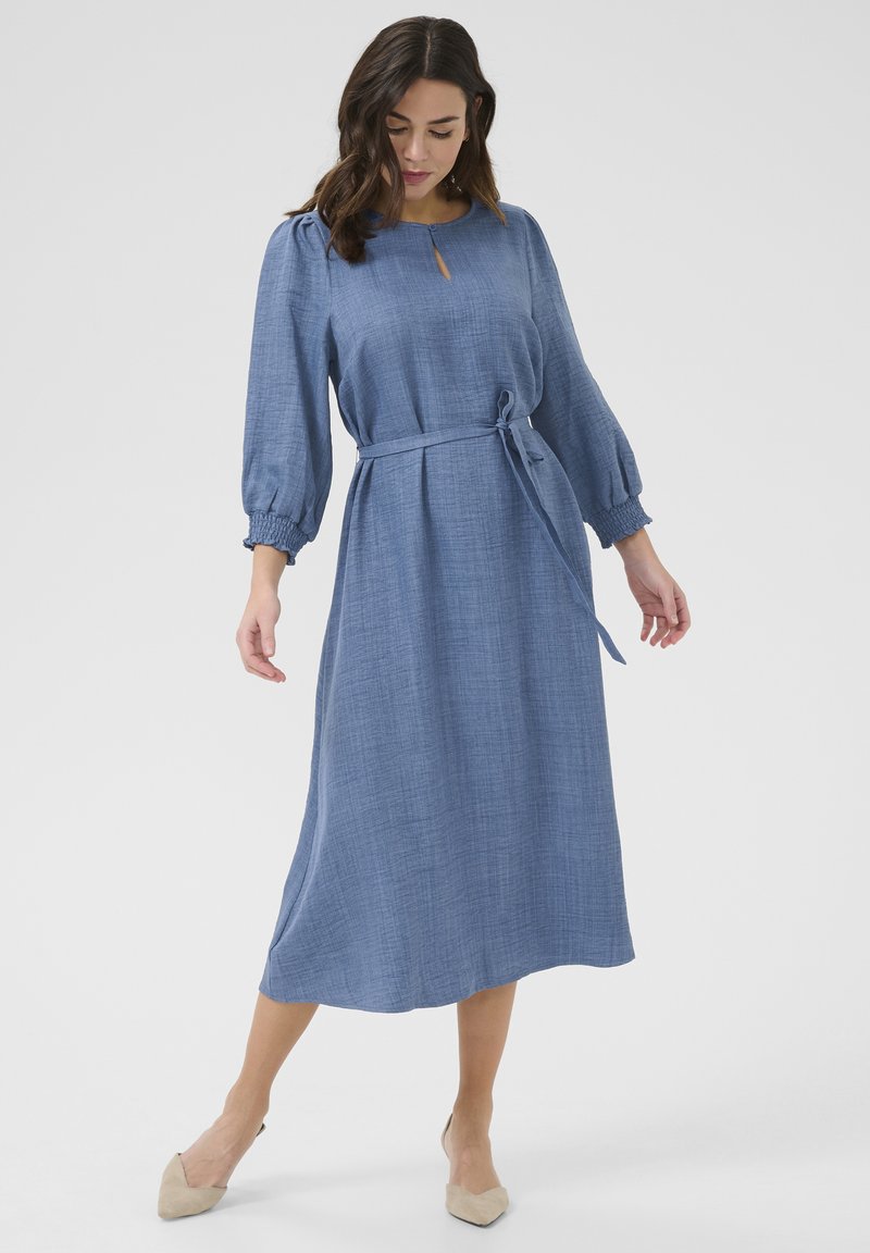 Robe midi bleu à manches longues avec un tissu texturé. Caractéristiques d'un décolleté en forme de clé et d'un lien en tissu à la taille. Silhouette douce et fluide.