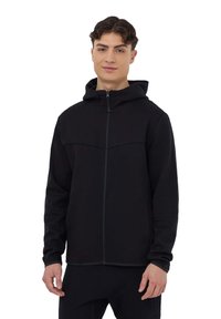 Felpa nera con zip realizzata in tessuto morbido, dotata di cappuccio e di una cucitura sul petto. Maniche lunghe con una vestibilità rilassata e senza loghi visibili.