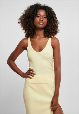 Top din tricot cu rigle, de culoare galben deschis, cu decolteu în V adânc, asortat cu o fustă până la genunchi, care prezintă o slit lateral.