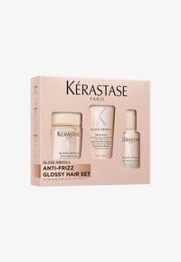 Zestaw Kérastase Gloss Absolu Anti-Frizz w różowym pudełku; zawiera trzy produkty z białymi i iryzującymi akcentami.