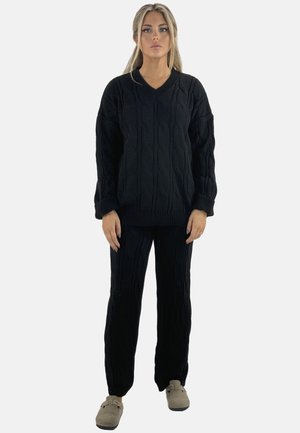 Sort strikket sweater og matchende bukser med et kabelmønster. Sweateren har V-hals, løs pasform og ribbetrukne cuffs; bukserne har lige ben.