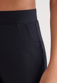 Marinblå träningsbyxor med mjuk elastisk midja och snedställda framfickor. Slät yta; figurnära passform för komfort och flexibilitet.