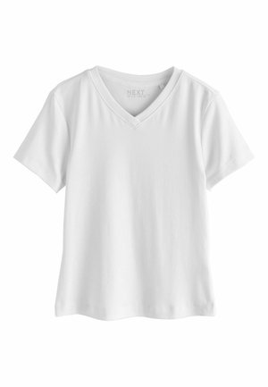 Ung kvinde med kort krøllet sort hår iført en hvid V-hals T-shirt, der kigger let til siden mod en ensfarvet baggrund.