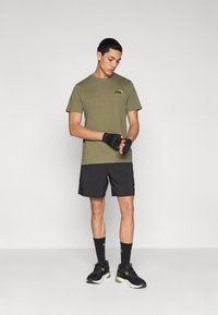 Πράσινο βαμβακερό T-shirt με μαύρο λογότυπο Puma, συνδυασμένο με μαύρο σορτς, μαύρα γάντια, μαύρες κάλτσες και μαύρα/πράσινα αθλητικά παπούτσια.