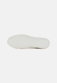 White sneaker sole with textured rubber, featuring a wavy pattern and grooves for grip. Clean design, suitable for casual wear.