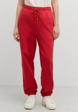 Rode sweatpants van zacht materiaal, met een elastische tailleband met een trekkoord, boorden bij de enkels en zijzakken.