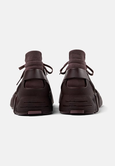 Dark brown high-top sneakers with a textured fabric upper, rubber accents, and tied laces, featuring a cushioned knit collar for comfort.