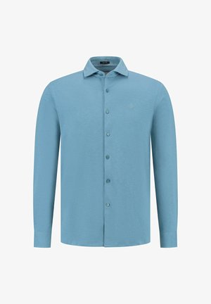 Világoskék, hosszú ujjú ing gombos elülső résszel, gallérral és diszkrét logóval a mellkason. Az anyag lágy kinézetű, sima textúrával rendelkezik.