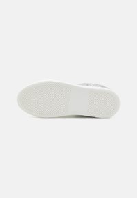 Witte sneakerzool met een gestructureerd rubberen oppervlak met een zigzagpatroon, een glad middelgedeelte en een ronde neus.