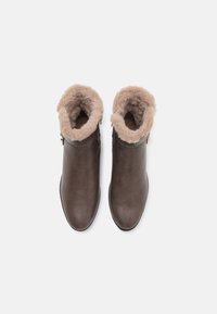 Bottines en cuir marron avec une doublure en fourrure beige douillette, bout arrondi, fermeture éclair sur le côté et texture lisse.