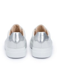 White sneakers with rounded shape, leather upper, metallic silver heel accents, smooth texture, and white rubber soles.