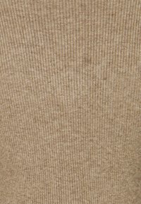 Tissu en tricot côtelé beige avec une texture douce et des lignes verticales, présentant un motif homogène et un léger éclat.