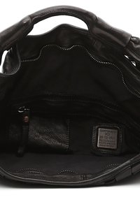Interno di una borsa a tracolla in pelle nera con texture liscia, tasca con zip e un'etichetta con la scritta "CAMPOMAGGI," made in Italy, caratterizzata da cuciture ondulate.