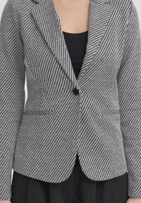 Blazer a righe in bianco e nero, con chiusura a un solo bottone, revers a incavo e tasche laterali. Tessuto liscio con finitura testurizzata.