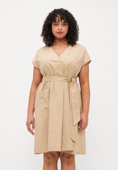 Beige wrap dress with short sleeves, a V-neck, side pocket, and tied waist, made from a lightweight, smooth fabric.