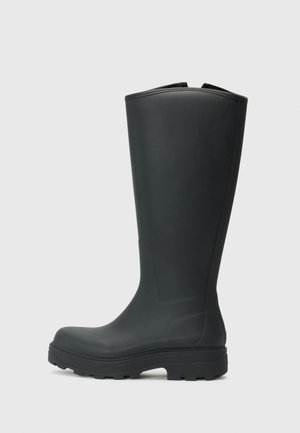 Bottes en caoutchouc noires à hauteur de genou, avec un bout rond et une semelle texturée pour une meilleure adhérence. Fini lisse avec un léger éclat et des coutures décoratives sur les côtés.