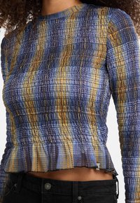 Gestructureerde lange mouw top met een blauw, geel en paars ruitpatroon, voorzien van een gerimpelde zoom en elastische smocking voor een aansluitend ontwerp.