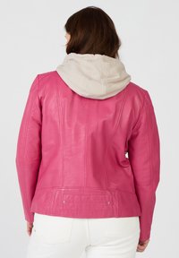 Ljust rosa läderjacka med en ljus beige huva, med sömnadsdetaljer och en åtsittande passform, kompletterad med en bakficka.