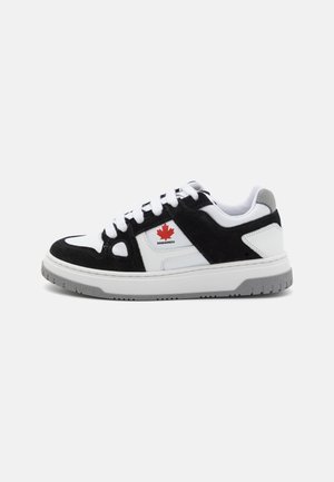 Sneakers in suede nera e pelle bianca presentano un logo a foglia di acero rossa, spesse stringhe bianche e una suola in gomma grigia con battistrada testurizzato.