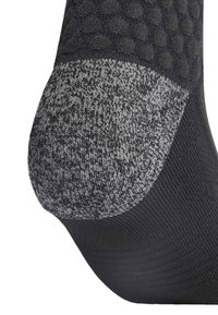 Calcetín negro con un talón texturizado gris; presenta un cuerpo liso con un patrón sutil. El talón muestra una estructura de punto mixto para mayor durabilidad.