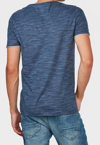 Mörkblå kortärmad T-shirt i texturerat tyg med rundad halsringning och subtilt melerat mönster, bakvy med denimjeans.