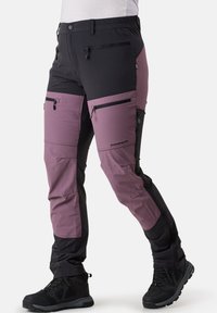 Pantaloni outdoor realizzati in una miscela di nylon, con blocchi di colore neri e mauve, numerose tasche con zip e un design a gamba affusolata.