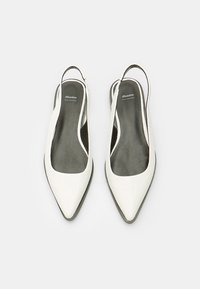 Scarpe slingback bianche in pelle con design a punta, texture liscia e soletta nera. Presentano un sottile cinturino sul tallone.