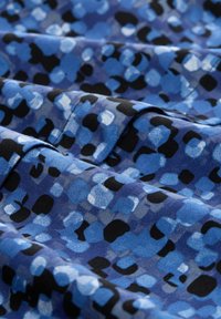 Blue and black patterned fabric featuring large, irregular shapes in various shades of blue, with a smooth texture and slight sheen.