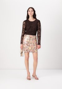 Mustmust pikkade varrukatega must pitsi topp, millele on kokku sobitatud roosa ja beež sequins lillemustriga mini seelik. Aksessuaariks on väike beež käekott.