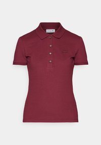 Polo slim fit à manches courtes de couleur bordeaux avec col, quatre boutons, et un petit logo crocodile brodé sur la poitrine.