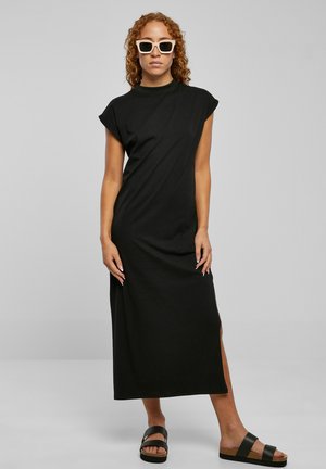 Black cotton maxi dress with short rolled sleeves and side slit. Paired with black platform sandals and square white sunglasses.