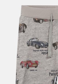 Γκρίζο ύφασμα με εκτυπωμένα αντίκες αγωνιστικά αυτοκίνητα, συμπεριλαμβανομένου ενός μπλε που φέρει την ένδειξη "legend style race 1952" και ενός κόκκινου που φέρει την ένδειξη "classic car."