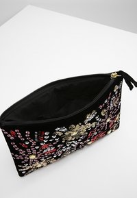 Svart tygkuvert med intrikata blommönster i paljetter i röd, guld och silver. Dragkedjestängning, insidan är fodrad och rymlig.