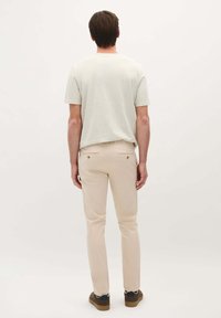 Vaaleanharmaa lyhythihainen t-paita yhdistettynä vaaleanbeigeihin slim fit -farkkuihin ja ruskeisiin kenkiin. Yksinkertainen muotoilu, puuvillamateriaali, huomaamattomat värit.