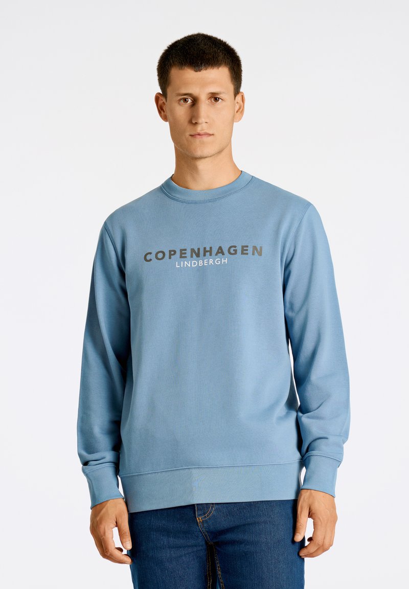 Ljusblå sweatshirt med ribbad muddar och nederkant, med "COPENHAGEN LINDBERGH" tryckt i fetstil på framsidan.