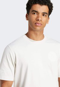 Kortærmet hvid T-shirt lavet af blødt stof, med rund halsudskæring og et diskret logo på venstre bryst.