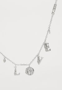 Collier en chaîne en argent avec des lettres suspendues formant le mot "AMOUR", ornées de décorations et d'un pendentif circulaire avec des strass.