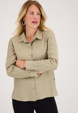 Licht olijfgroene lange mouw shirt met een knoopsluiting aan de voorkant en studs langs de mouwen. Zacht materiaal, losse pasvorm.