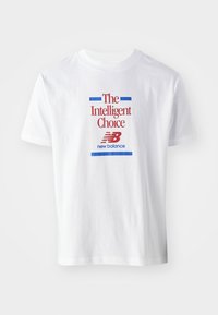 T-shirt de algodão branca com mangas curtas, apresentando texto vermelho e azul com as inscrições "A Escolha Inteligente" e o logótipo "new balance" abaixo.
