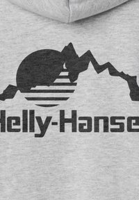 Sudadera gris con un gráfico de montaña negra y sol, acompañado de líneas horizontales, junto con el texto "Helly-Hansen" en fuente negrita debajo del diseño.