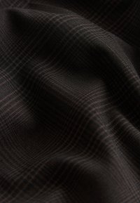 Tissu foncé avec un motif à carreaux subtil dans des nuances de noir et de marron, présenté avec des plis doux et des détails de texture.